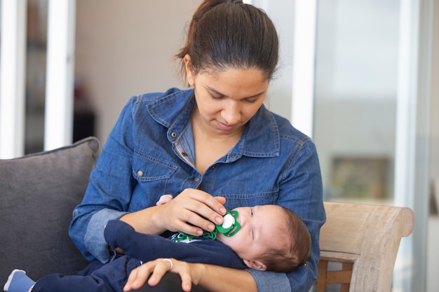 Photo femme en chemise en jean bleu, avec bébé endormi.