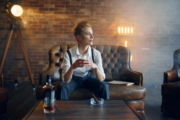 Femme en chemise et pantalon avec whisky et cigare