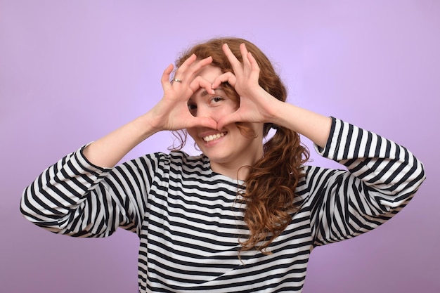 Photo une femme en chemise rayée avec les mains en forme de coeur