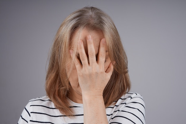 Une femme en chemise rayée souffre de douleur