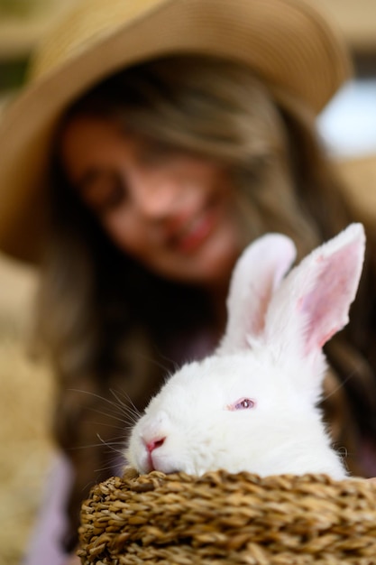 Photo une femme en chemise rose jouant avec un lapin blanc.