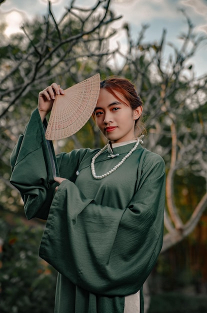 Photo une femme en chemise verte et chapeau pose devant un arbre.