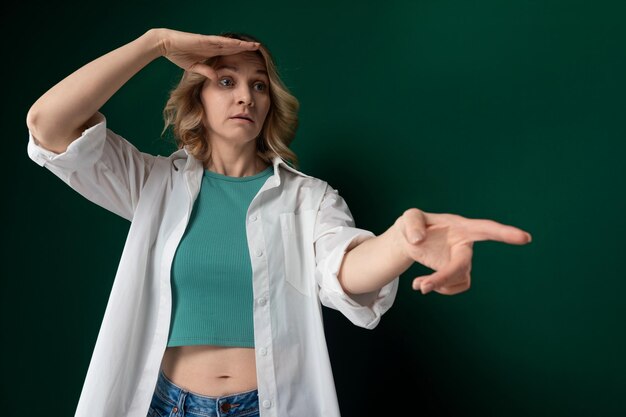 Photo une femme en chemise verte pointant vers quelque chose.