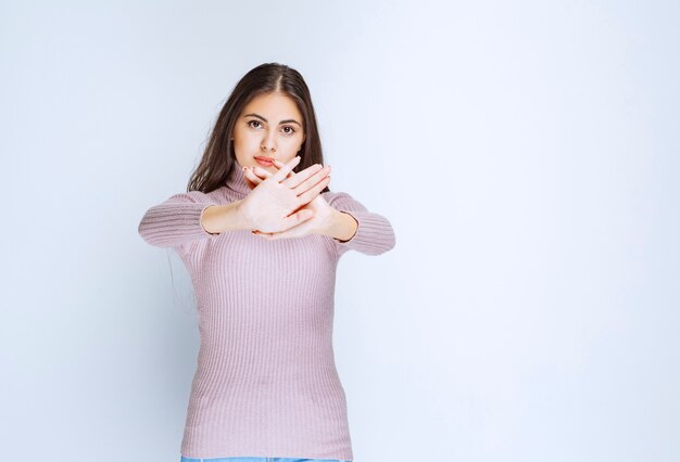 femme en chemise violette rejetant quelque chose avec des gestes de la main.