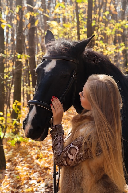 Femme avec un cheval pour une promenade dans la forêt d'automne