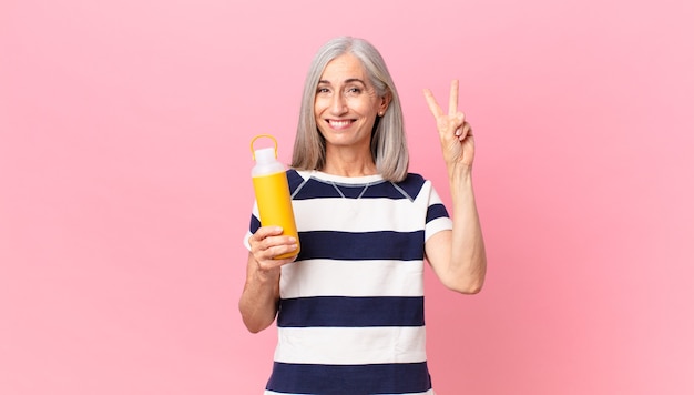 Femme de cheveux blancs d'âge moyen tenant un thermos de café