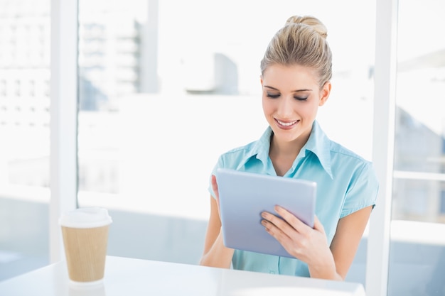 Femme chic souriante avec tablette tout en faisant une pause