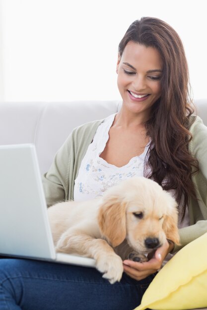 Femme avec un chien à l&#39;aide d&#39;un ordinateur portable sur le canapé