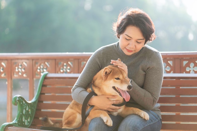 Femme avec un chien assise sur un banc