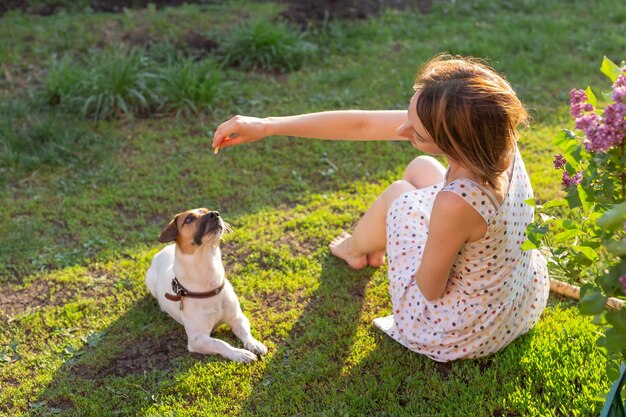 Une femme avec un chien assise sur l'herbe.