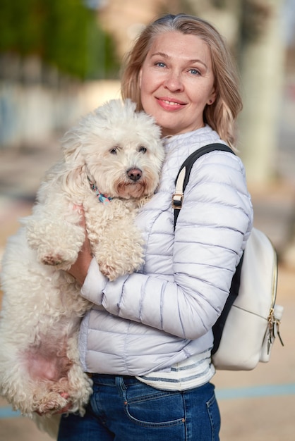 Femme avec chien blanc moelleux dans la ville d'été