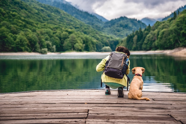 Femme avec un chien debout sur la jetée au bord du lac