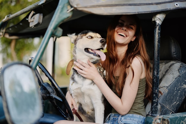 Femme et chien husky voyageant joyeusement en voiture sourire avec des dents tombent à pied avec un animal de compagnie voyage avec un ami chien câlins et danses