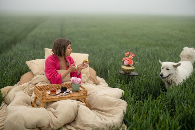 Femme avec un chien sur un lit sur un champ vert à l'extérieur