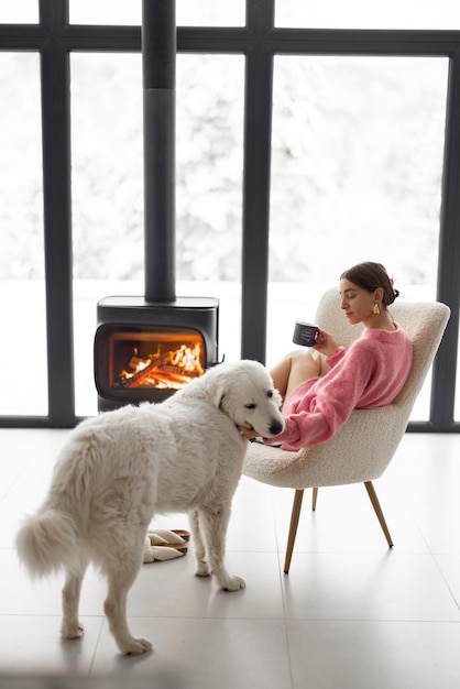 Femme avec chien à la maison avec cheminée en hiver