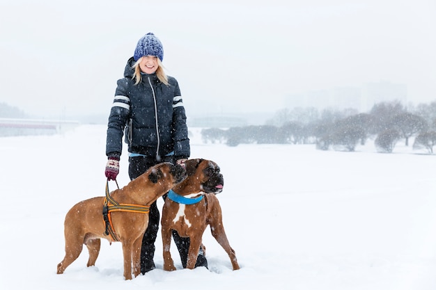 Femme avec des chiens boxer sur une journée d'hiver enneigée sur une promenade