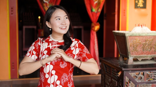 Femme chinoise asiatique dans une robe cheongsam avec félicitations gest à vihara