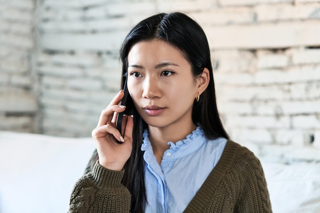 Une femme chinoise au téléphone, une conversation confortable sur le canapé.