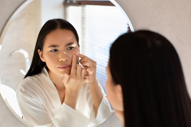 Femme chinoise bouleversée touchant son visage en appuyant sur le bouton