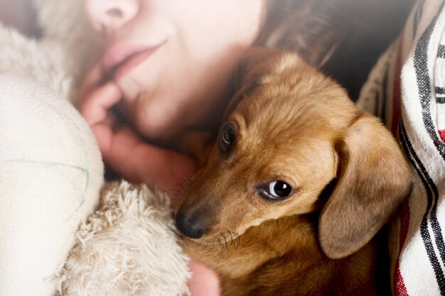 Photo une femme avec un chiot couché sur le lit à la maison