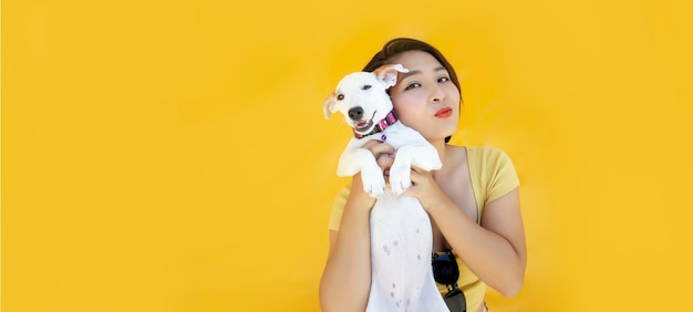 Femme avec chiot jack russel embrasse avec amour chien prend soin de l'animal porte des vêtements décontractés sur fond jaune isolé espace de copie pour votre promo