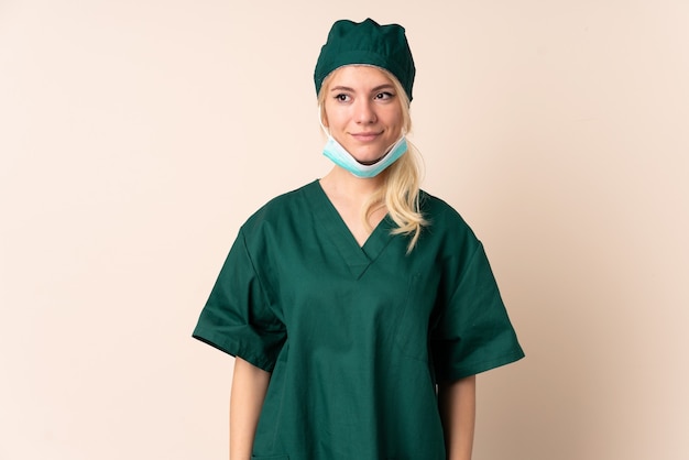 Femme chirurgien en uniforme vert sur debout isolé et regardant sur le côté