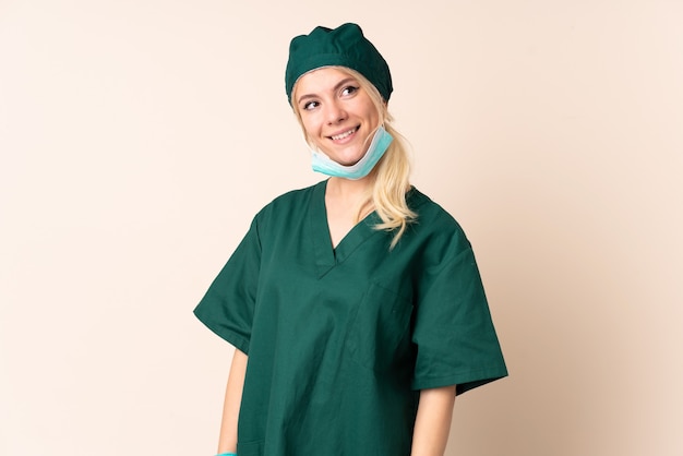 Femme chirurgien en uniforme vert sur isolé en riant et en levant