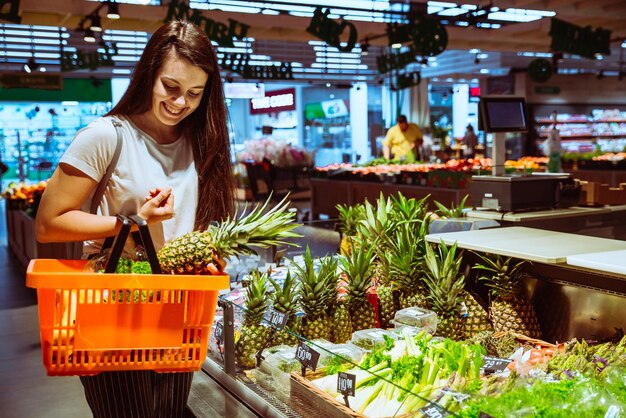 Femme choisissant l'ananas dans l'épicerie
