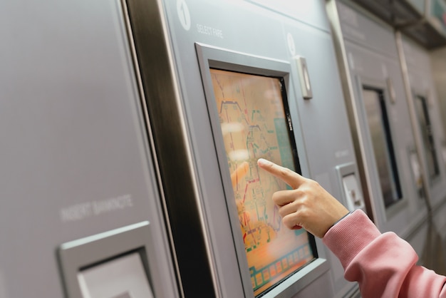 Femme choisissant la destination sur un distributeur de billets de métro.