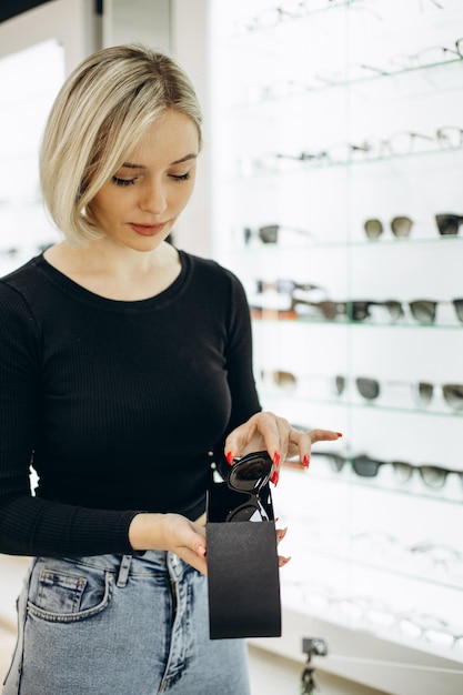 Femme choisissant des lunettes de soleil au magasin