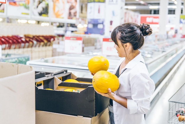 Femme choisissant des melons en épicerie