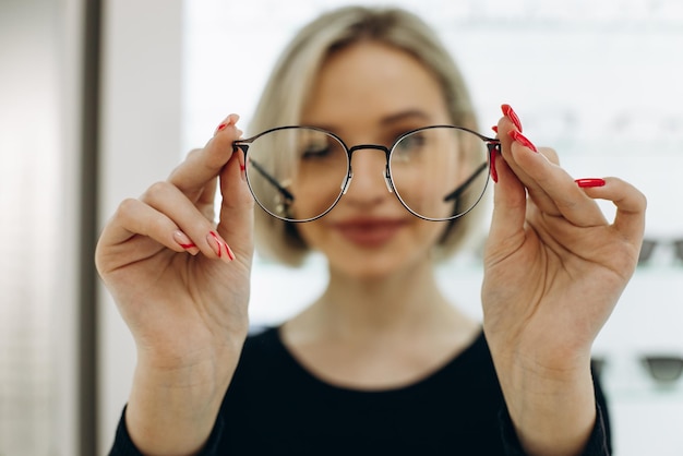 Femme choisissant une paire de lunettes au magasin d'optique