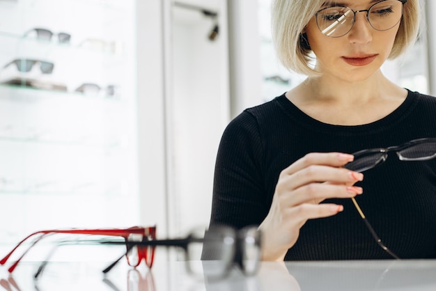 Photo femme choisissant une paire de lunettes au magasin d'optique