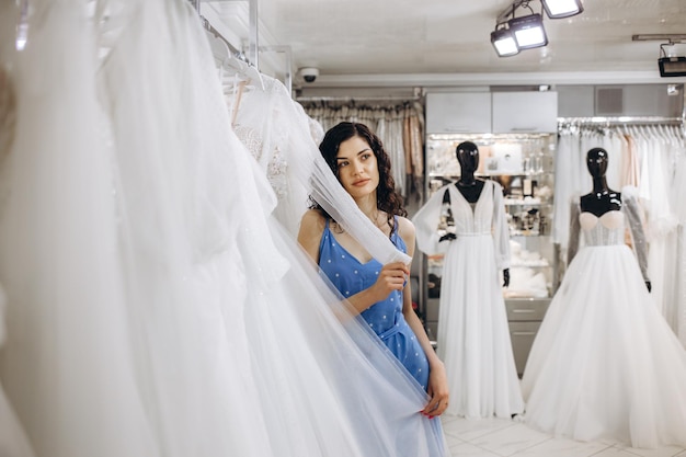 Femme choisissant la robe de mariée dans la boutique