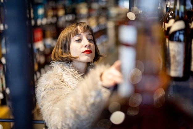 La femme choisit l'alcool fort dans le supermarché