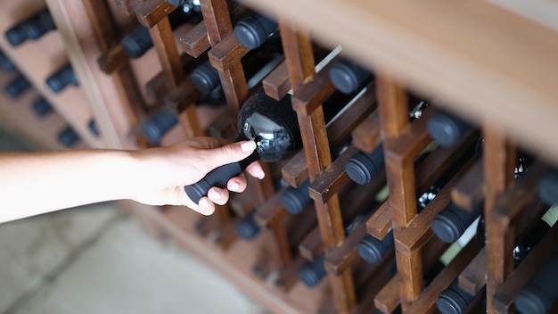 Femme choisit une bouteille de vin en gros plan de cave