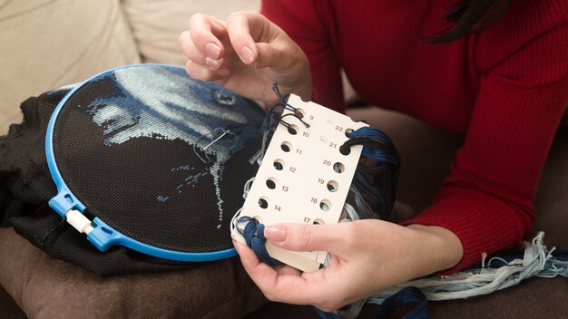 La femme choisit le fil pour la broderie par couleur et nombre