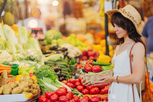 La femme choisit des fruits et légumes au marché alimentaire.