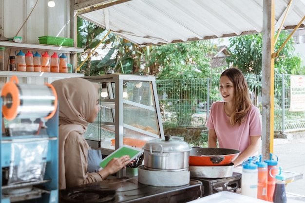 La femme choisit la nourriture un menu qu'un vendeur apporte