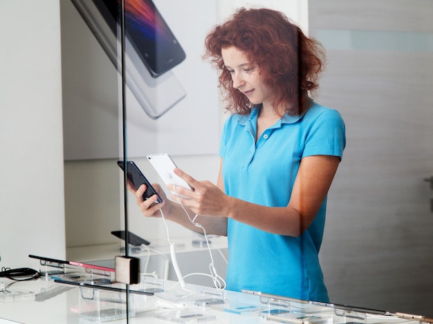 Femme choisit un smartphone dans un magasin