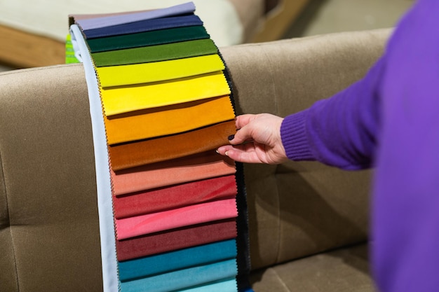 La femme choisit le tissu sur le canapé Une femme regarde des échantillons de tissus Choisit la couleur du canapé Contexte de l'industrie textile Catalogue de tissus