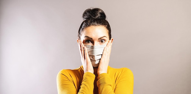 une femme choquée a l'air effrayée de porter un masque de protection contre l'épidémie de coronavirus COVID-19.