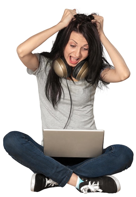 Femme choquée assise avec les jambes croisées avec un ordinateur portable et criant - isolée
