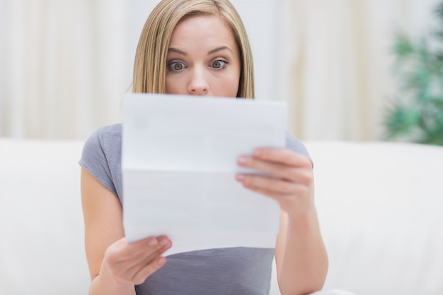 Femme choquée, lecture de lettre dans le salon