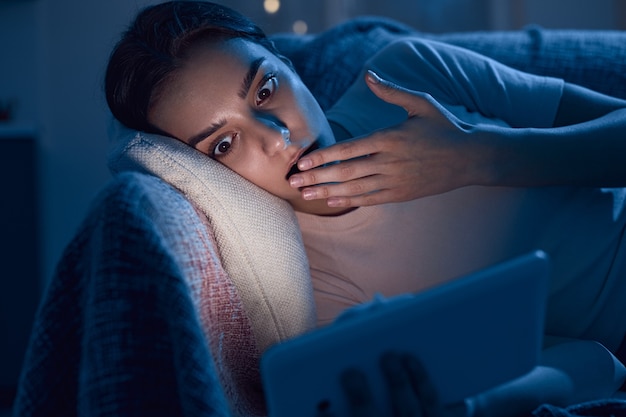 Femme choquée lisant des nouvelles la nuit