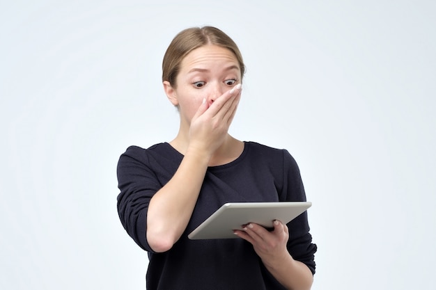 Femme choquée regardant tablette numérique avec surprise