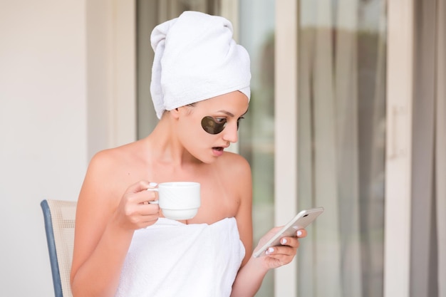 Femme choquée ou surprise dans les patchs sous les yeux lisant un message et buvant du café à la terrasse de l'hôtel resort concept de vacances du matin mauvaise nouvelle