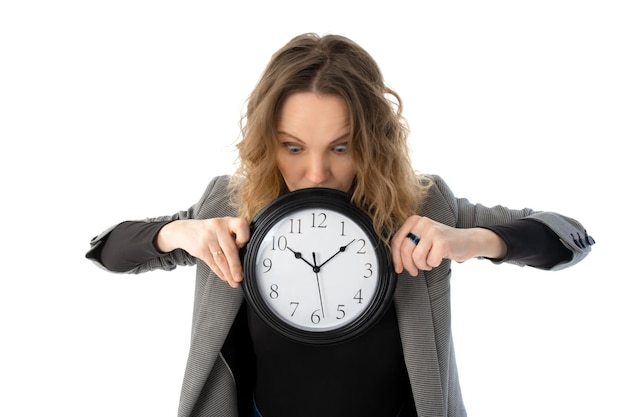 Une femme choquée tient une grande horloge dans ses mains sur un fond blanc Isolé sur fond blanc Concept de date limite