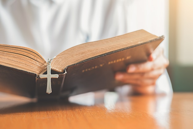 Femme chrétienne priant sur la Sainte Bible. Les mains jointes dans la prière, une Sainte Bible dans l'église conce