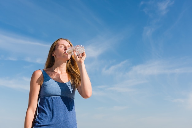 Femme, à, ciel, fond, boire, eau, dehors